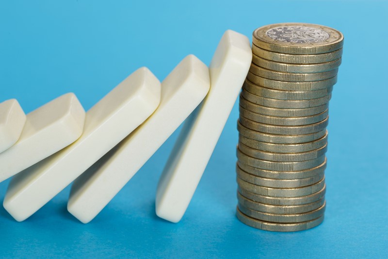 Dominostenen die tegen een stapel euromunten valt